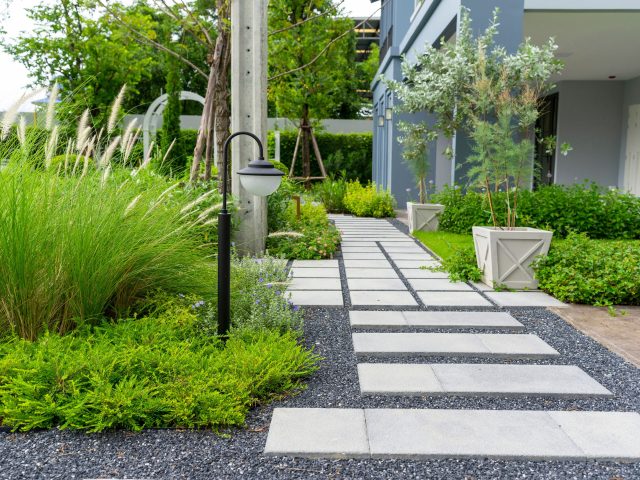 Modern design home garden landscaping. Flower garden and green plant with brick border and pedestrian pathway.